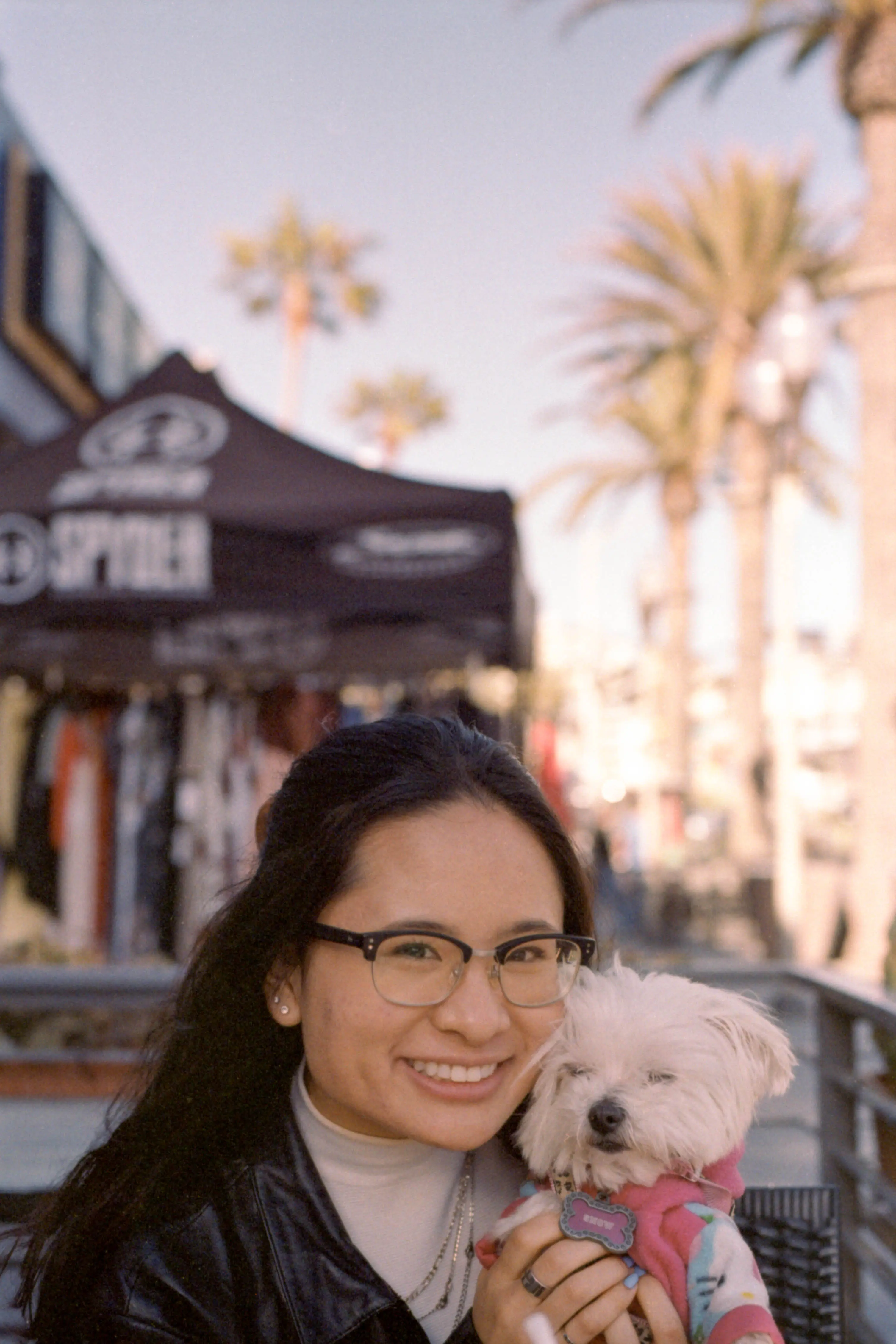 A woman holding her dog up and smiling. The dog, however, looks annoyed.